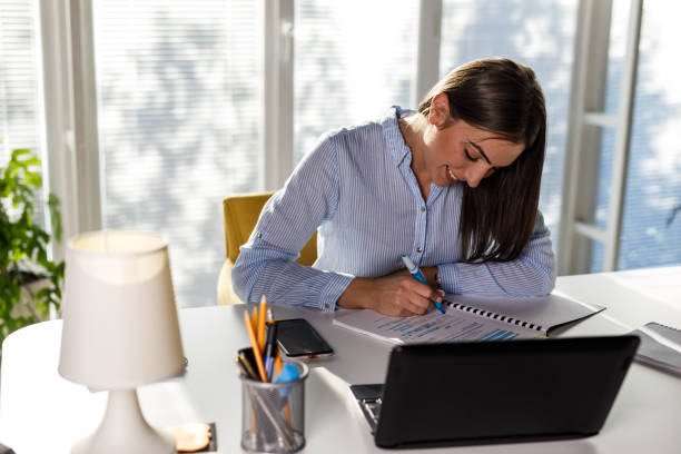 istock Young woman sitting at home office desk, highlighting important notes while studying 1446222250