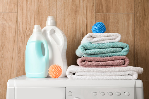 Dryer balls, stacked clean towels and detergents on washing machine