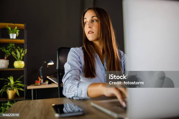 Diligent Young Woman Typing Data On Laptop At Her Desk At The Office Stock Photo - Download Image Now