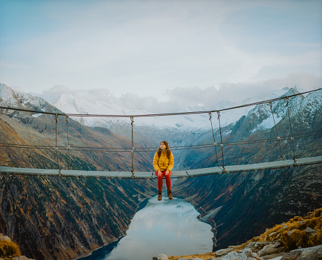 Young Caucasian woman on the bridge on the background of lake in Austrian Alps shot on film