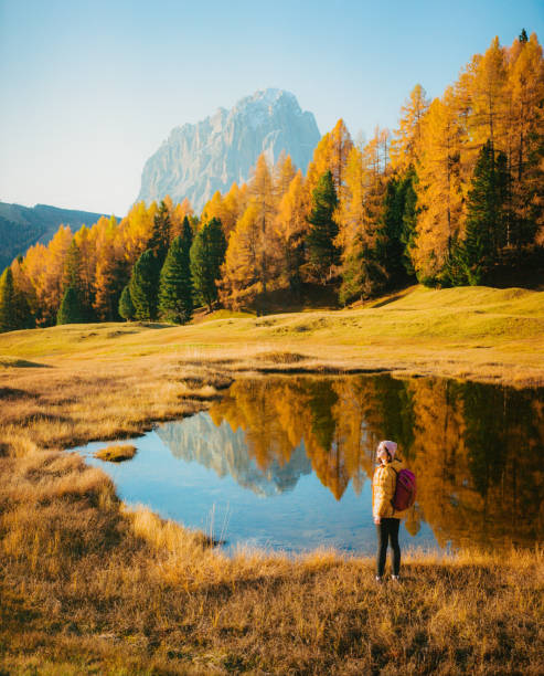 woman hiking on the background of the lake in dolomites in autumn - travel vertical tourist switzerland imagens e fotografias de stock