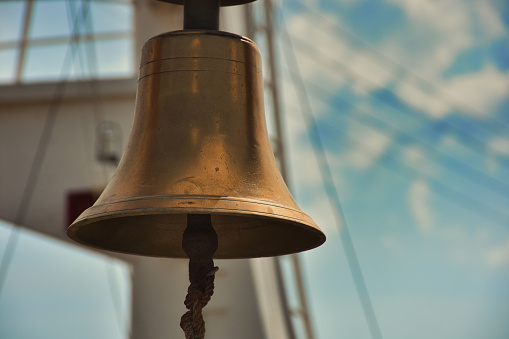 Antique brass, copper ship bell on background of blue sky