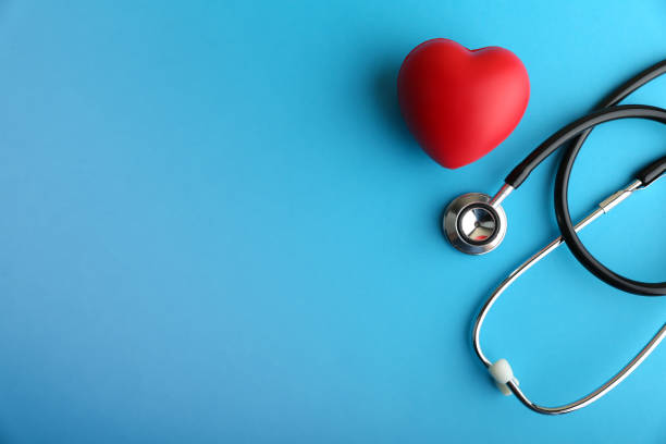 el corazón rojo y el estetoscopio están sobre fondo azul - healthcare and medicine fotografías e imágenes de stock