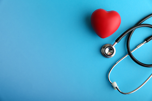 red heart and stethoscope are on blue background top view with copy space