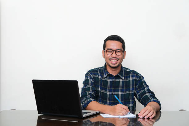istock Adult Asian man smiling while sitting in his working table 1446230369