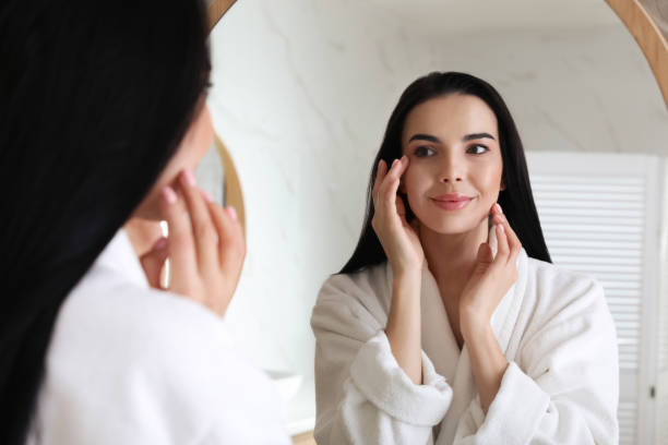 istock Beautiful young woman looking at herself in bathroom mirror 1446230814