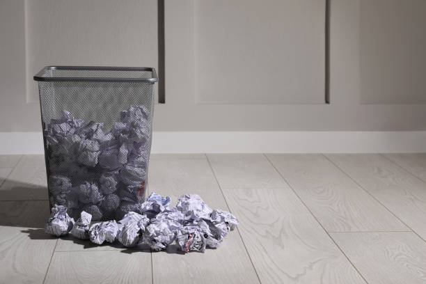 istock Trash bin with paper on floor near white wall, space for text. Recycling rubbish 1446232157