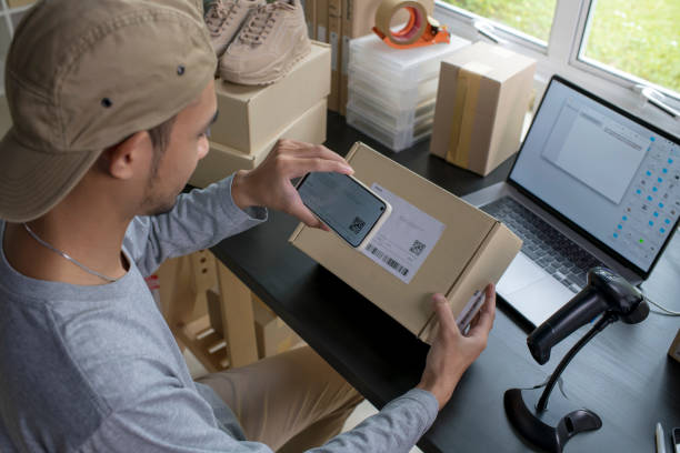 istock Asian man business owner using smartphone scanning barcode on delivery parcel. 1446232411