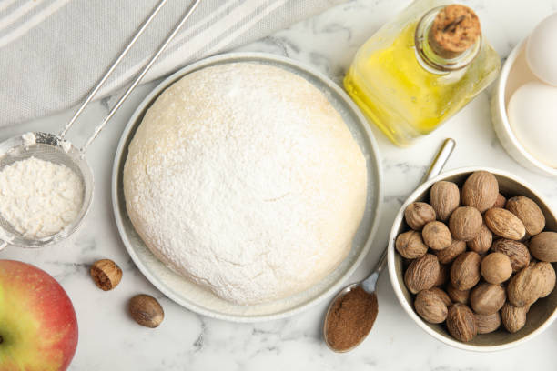istock Raw dough, nutmeg seeds and other ingredients for pastry on white marble table, flat lay 1446232515