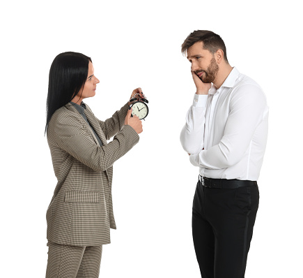 Business woman with alarm clock scolding employee for being late on white background