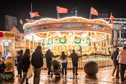 Christmas market scene with people and spinning carousel at night