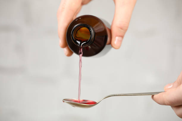 istock Woman pouring cough syrup into spoon on light background, closeup 1446235904