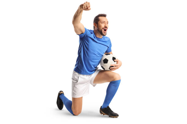 istock Football player with a ball kneeling and gesturing win 1446237369
