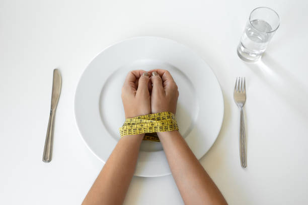 knife and fork near empty plate - dieting healthy eating healthy lifestyle tape measure imagens e fotografias de stock