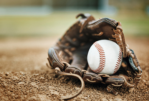 Baseball, leather glove and ball on pitch sand after fitness, workout or training for match or competition. Zoom, texture and softball mitt on field for sports team, wellness exercise or stadium game