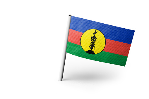 Small paper flag of New Caledonia pinned. Isolated on white background. Horizontal orientation. Close up photography. Copy space.