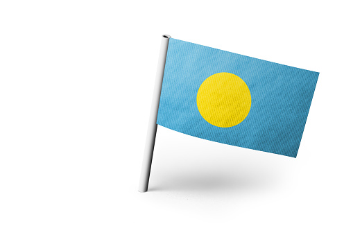 Small paper flag of Palau pinned. Isolated on white background. Horizontal orientation. Close up photography. Copy space.