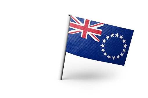 Small paper flag of Cook Islands pinned. Isolated on white background. Horizontal orientation. Close up photography. Copy space.
