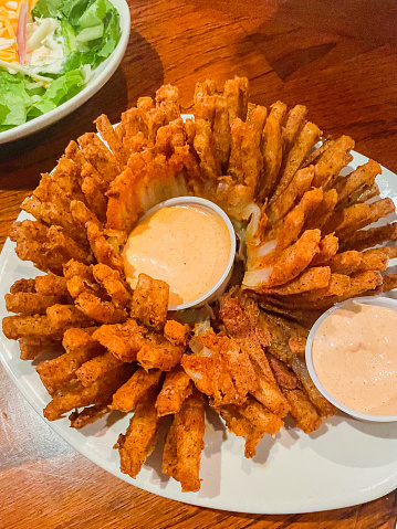 Fried blooming onion flower blossom with dipping sauce at an Outback steakhouse restaurant