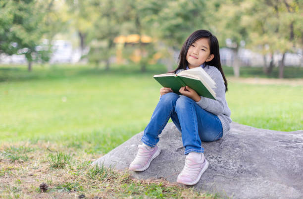 istock Reading Little Girl Sitting on Stone 1446252193