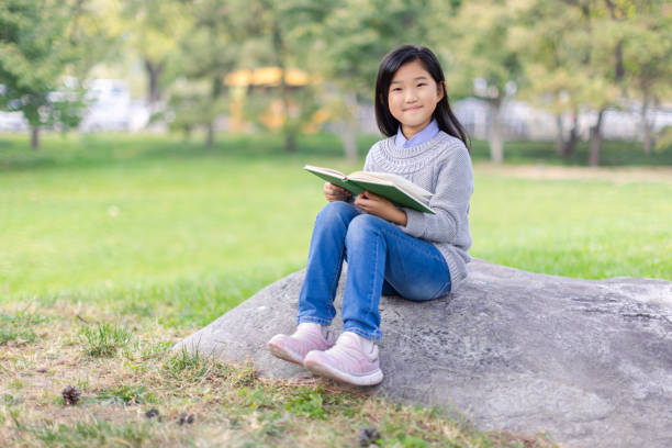 Reading Little Girl Sitting on Stone stock photo
