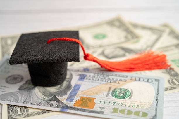 istock Graduation gap hat on US dollar banknotes money, Education study fee learning teach concept. 1446253262