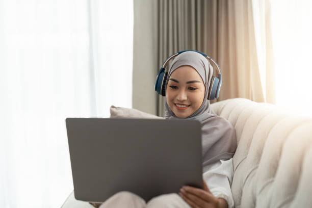 mulher muçulmana asiática tendo videoconferência em seu laptop em casa, aprendendo on-line ou trabalhando em casa conceito - room service audio - fotografias e filmes do acervo
