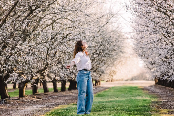 istock Woman enjoying springtime among blooming almond trees 1446258110