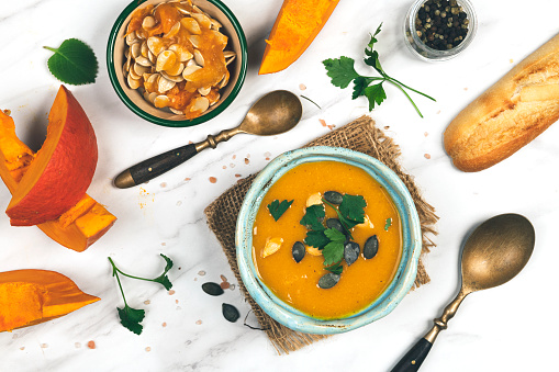 Woman eating homemade, fresh and good looking  pumpkin soup in white bowl on beautiful background