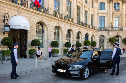 Paris, France - July 17th 2022: Two doormen welcome the guest who gets out of the taxi in front of the Ritz hotel in Paris