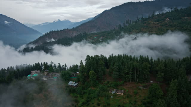 Forest and towns of Himalayas, clouds and fog, aerial drone shot