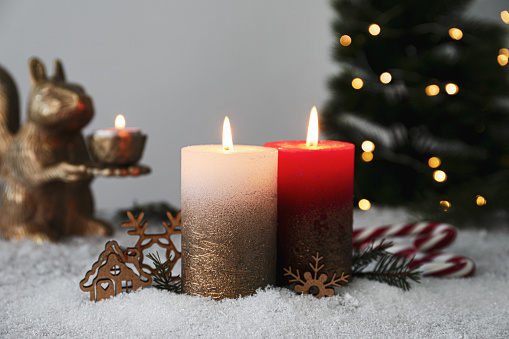 Burning candles and Christmas decor on artificial snow