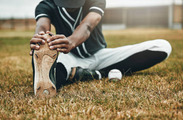 istock Baseball, player and stretching for game, training and workout on field, with ball and sportswear for health. Black man, athlete or doing exercise to prepare for game, match or fitness being healthy 1446267436