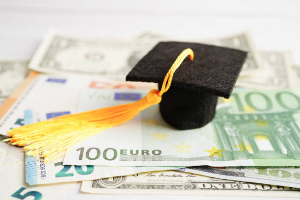 istock Graduation gap hat on Euro and US dollar banknotes money, Education study fee learning teach concept. 1446267518