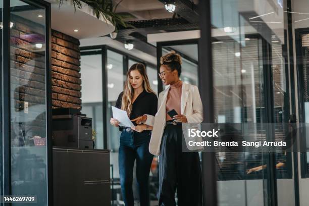 Young Female Employees Walking Down The Company Corridor Stock Photo - Download Image Now