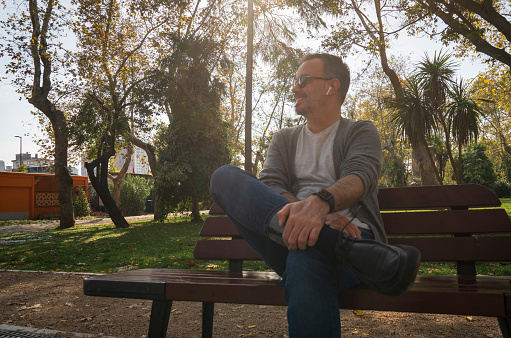 man relaxing sitting on a bench in a park