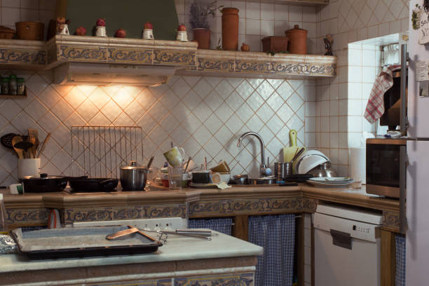 istock A rustic tile and ceramic kitchen with a stack of dirty dishes in the sink and a counter full of pots and pans. 1446275314