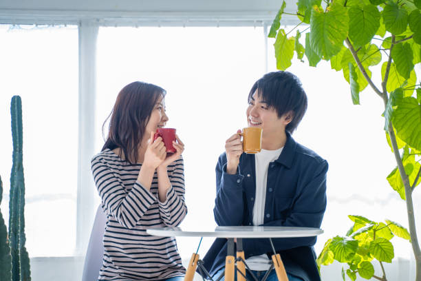 istock Young smiling conversational couple drinking coffee in bright living room 1446275856