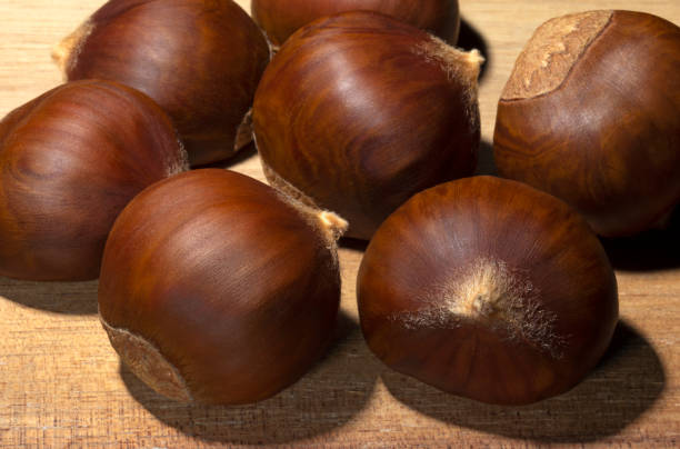 ricche castagne colorate sul blocco del macellaio - chestnut sweet food yellow group of objects foto e immagini stock