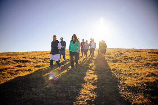 Group of Caucasian female and male, senior, mid and young adult people, hiking during sunny autumn day