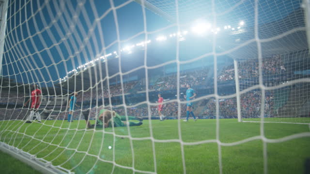 Soccer Football Championship Match on Stadium: Blue Team Player Kicks the Ball, Scores Goal, Goalkeeper Loses. Cup, World Tournament Winner. Sport Television Playback. Inside Goals Low Angle Camera