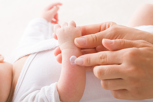 close up of a grand-grandmothers hand and small hands of 4 month old baby