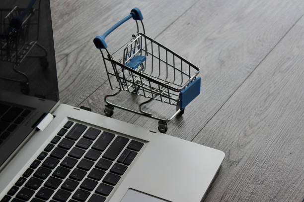 Laptop and mini shopping trolley on wooden table Laptop and mini shopping trolley on wooden table. Online shopping concept hashish shop online stock pictures, royalty-free photos & images