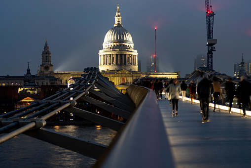 Millennium bridge over the Thames on a foggy day with St Paul's cathedral in the background. It is a long exposure with unrecognisable ghostly pedestrians in the foreground.