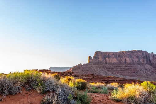 View of mesa butte formations with red orange rock color in Monument Valley canyons during sunset in Arizona with sunlight over cabin houses in campground