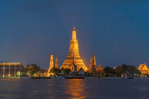 Temple of Dawn or Wat Arun with reflection of Chao Phraya River in Rattanakosin Island in architecture, Urban old town city, Bangkok skyline. downtown area, Thailand at night.