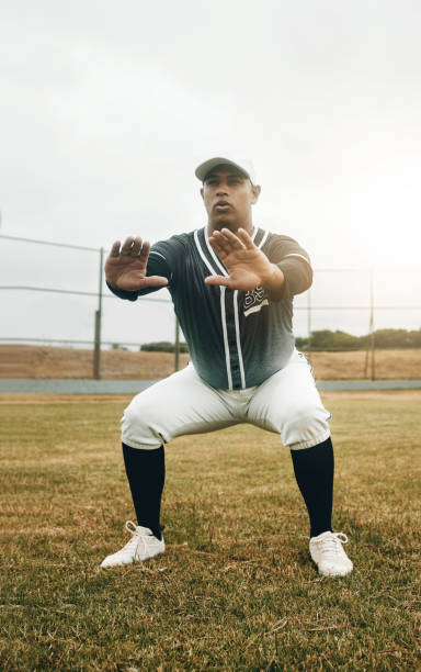 istock Baseball player, stretching and sports man doing squats on field for warm up exercise, workout and practice for match. Male athlete with tshirt and cap for health, wellness and energy on match pitch 1446298612