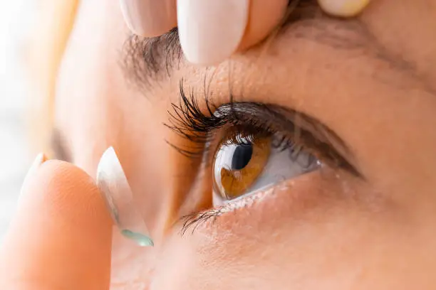 Photo of Close up woman applying contact eye lens.