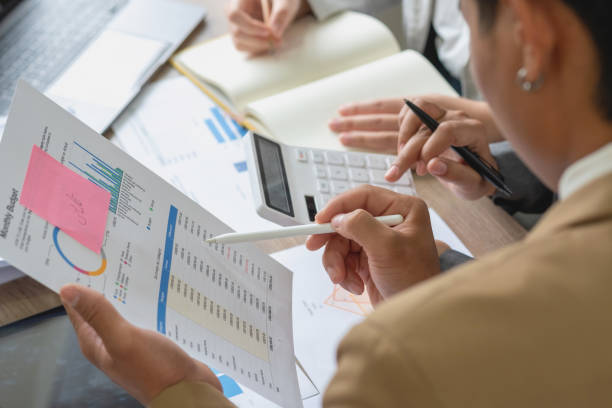 istock The company is team of marketers analyzes the company is profits using laptop computer graphs and calculators. 1446301062