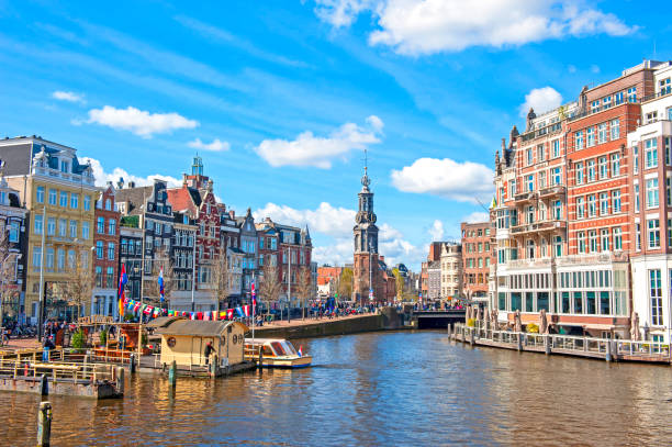 view of amsterdam canal and munttoren - grachtenpand stockfoto's en -beelden